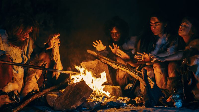 Ancient humans sitting around a fire
