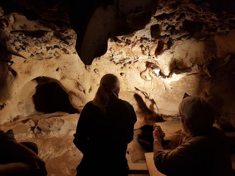 Archeologists in a cave on the new study, discussing the fingerprints.