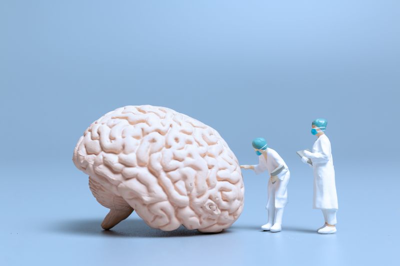 3d model of brain being examined by tiny toy doctors