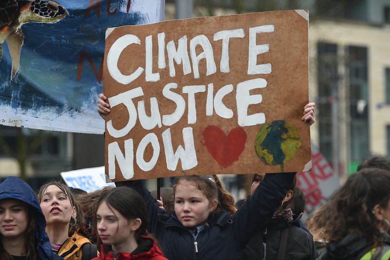 A young person at a protest in bristol holding a sign that says climate justice now