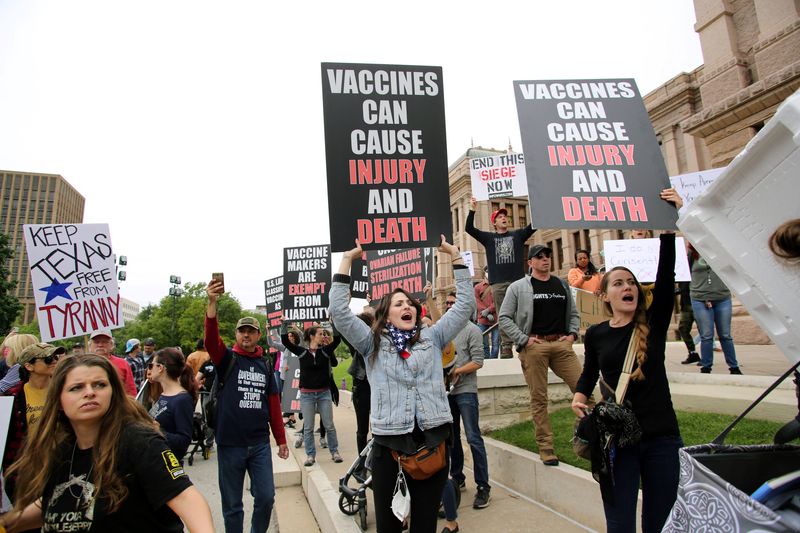 A group of Americans protesting vaccines while looking angry and holding angry looking signs. 
