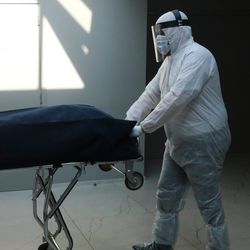 Mortuary workers in protective suits transport a coffin of a COVID-19 victim in Gilly, Belgium on Apri. 9, 2020.