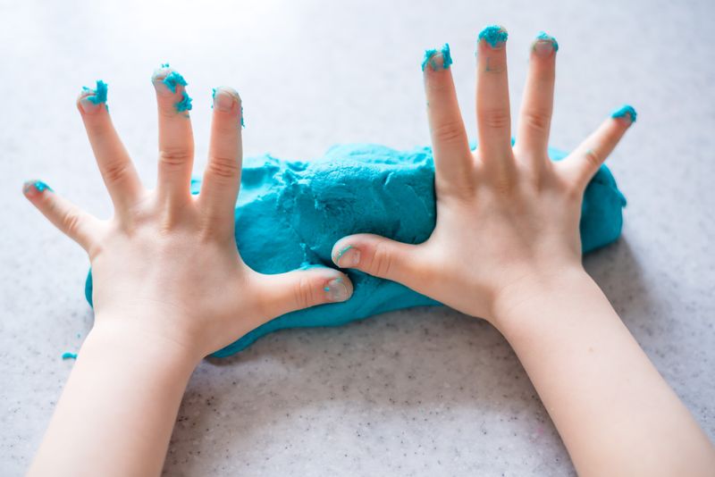 child's hands with bright blue plasticine