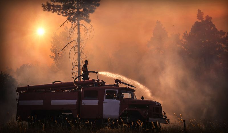Firefighter on a fire truck extinguishes wildfire caused by the climate crisis. 