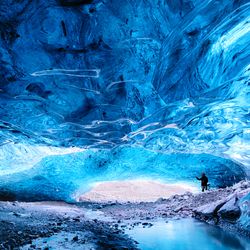 A man standing in a blue ice cave in Iceland