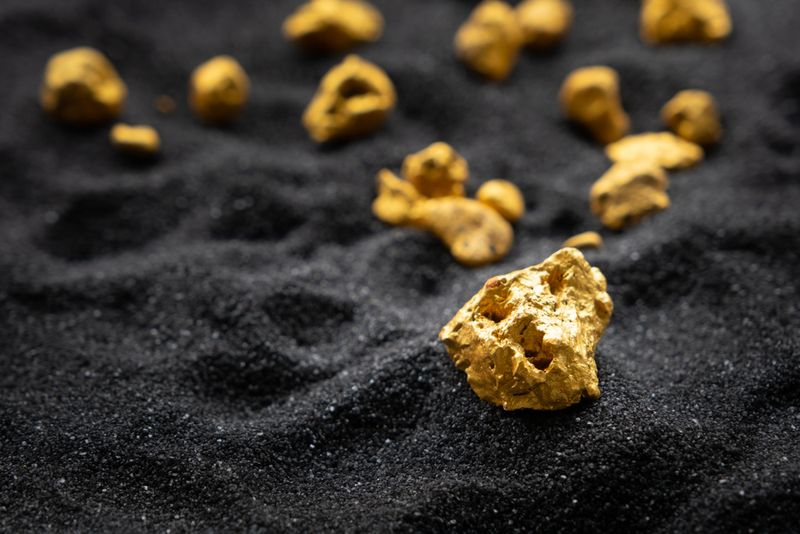 Gold nuggets on a black sandy surface