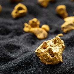 Gold nuggets on a black sandy surface