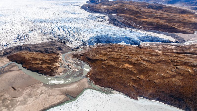 Greenlandic ice sheet melting glacier into river with tundra aerial view, near Kangerlussuaq, Greenland