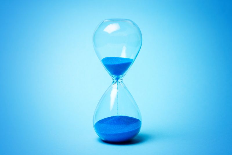 Hourglass with blue sand on a blue background