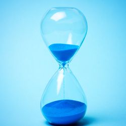 Hourglass with blue sand on a blue background