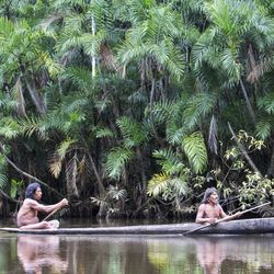 Two Huaorani people sail down a river in Ecuador's Yasuni national park