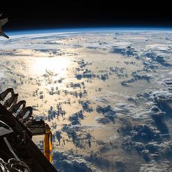 The Sun's glint reflects off the Pacific Ocean shadowed by a line of cumulonimbus clouds as the International Space Station orbited over the International Date Line about 253 miles above the Earth's surface.