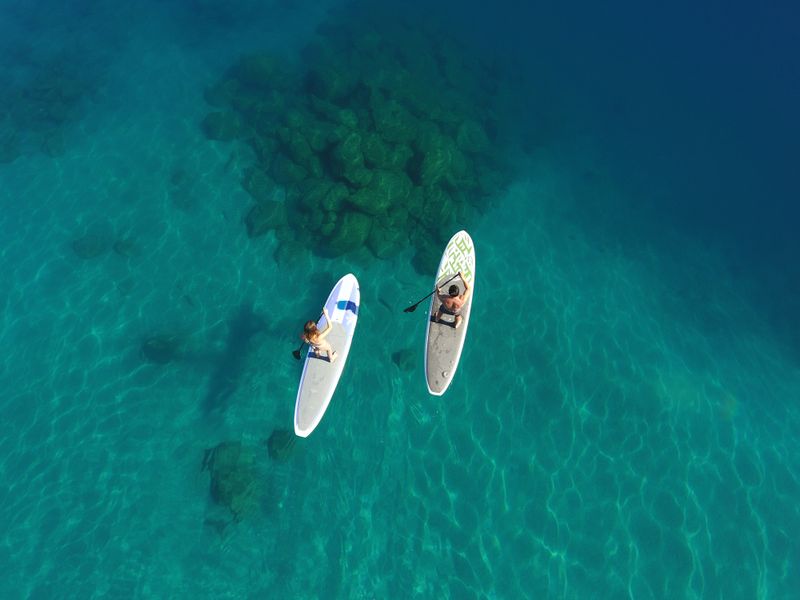 Looking down on two paddleboarders on the clear bright blue waters of lake tahoe 