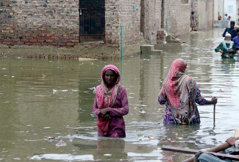 Residents wade through the flood on July 26 2022 in the Pakistani city of Hyderabad