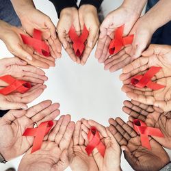 Group of hands holding red ribbonsymbolizing HIV/AIDS awareness