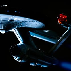  A model of the Starship Enterprise from the TV series Star Trek dramatically lit from below against a black background to replicate space.
