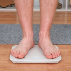 A man stands on the scales. The guy is weighing himself. Floor scales for health. Weight control.