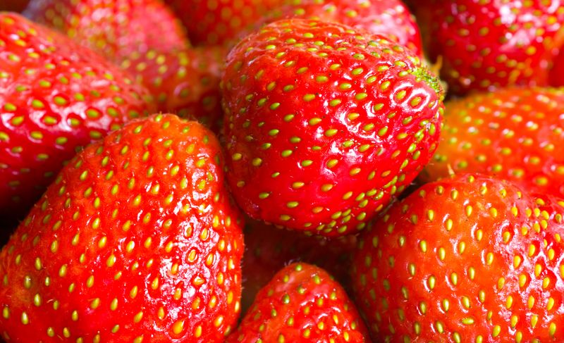Close up of a pile of strawberries with their achenes visible.