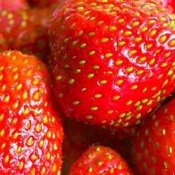 Close up of a pile of strawberries with their achenes visible.