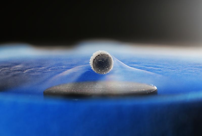 a superconducitng sphere is levitated above a magnet. the material is not a room temperature and the evaporation of liquid nitrogen is visible around it.
