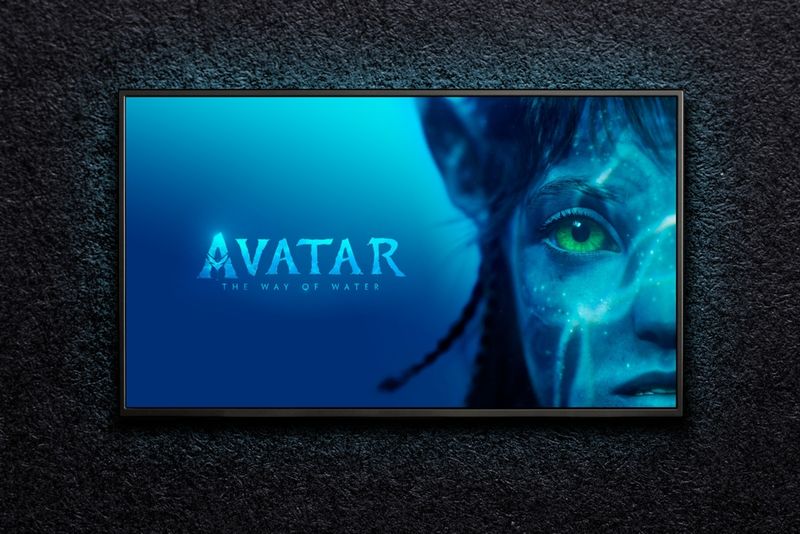 TV on black wall showing title card of Avatar the way of water alongside the face of a Na'vi