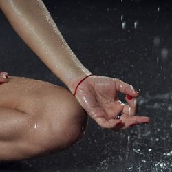 View of a person's knee and hand while they hold a lotus pose in the rain