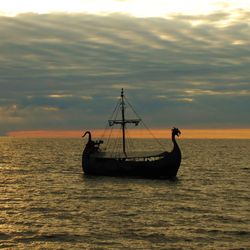 A photo of a Viking longboat heading towards a sunset.