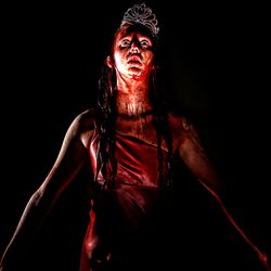 Woman in prom dress and tiara covered in blood