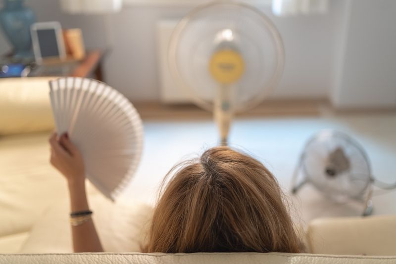 Woman sitting on sofa with several fans