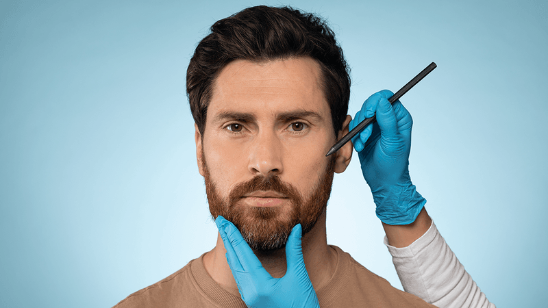 bearded man having his face examined by person in blue latex gloves