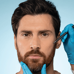 bearded man having his face examined by person in blue latex gloves