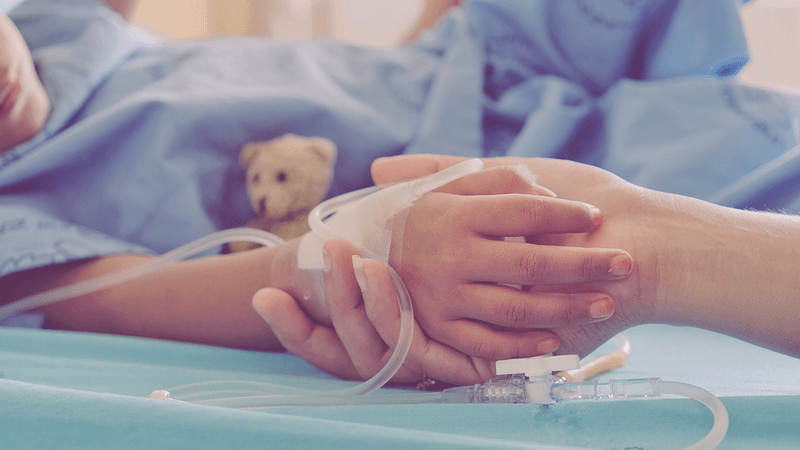 A child in hospital holding hands with an adult.