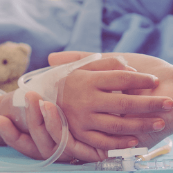 A child in hospital holding hands with an adult.