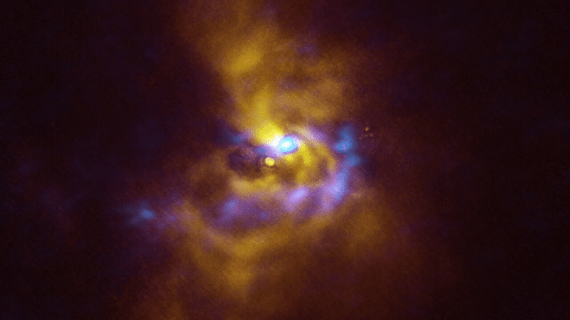 At the centre of this image is the young star V960 Mon, located over 5000 light-years away in the constellation Monoceros. Dusty material with potential to form planets surrounds the star.   Observations obtained using the Spectro-Polarimetric High-contrast Exoplanet REsearch (SPHERE) instrument on ESO’s VLT, represented in yellow in this image, show that the dusty material orbiting the young star is assembling together in a series of intricate spiral arms extending to distances greater than the entire Solar System.   Meanwhile, the blue regions represent data obtained with the Atacama Large Millimeter/submillimeter Array (ALMA), in which ESO is a partner. The ALMA data peers deeper into the structure of the spiral arms, revealing large dusty clumps that could contract and collapse to form giant planets roughly the size of Jupiter via a process known as “gravitational instability”.